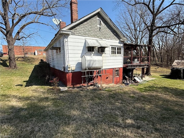 back of house featuring a lawn, a chimney, and heating fuel