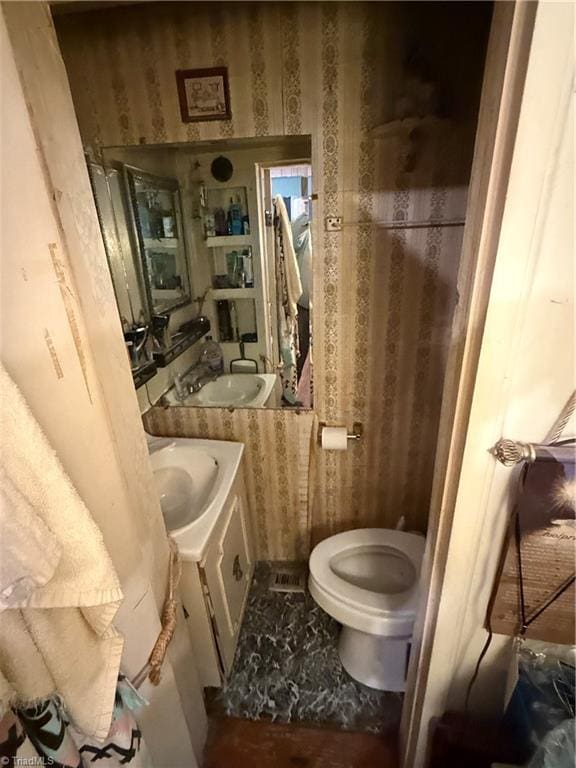 bathroom featuring wallpapered walls, toilet, and vanity