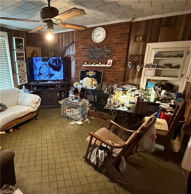 living area featuring wooden walls, ceiling fan, and a wood stove