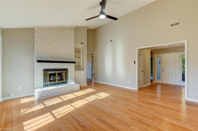 unfurnished living room with ceiling fan, light wood-type flooring, and a brick fireplace