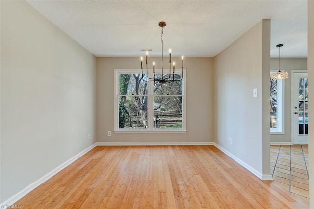 unfurnished dining area with light wood-type flooring and a chandelier