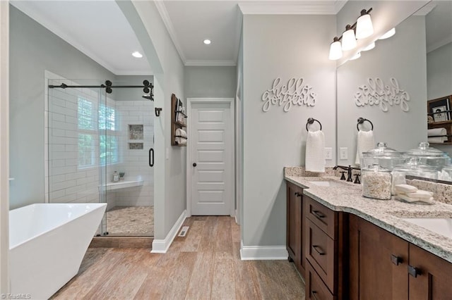 3922 Tam O Shanter Rd, Kernersville, NC 27284 - full bath featuring a soaking tub, double vanity, a shower stall, wood finished floors, and ornamental molding