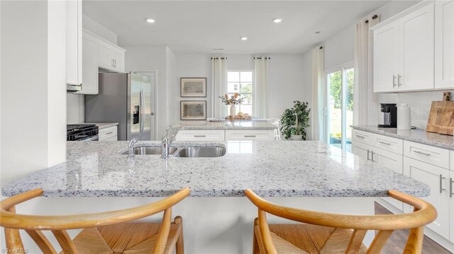 6617 Grogan Hill Rd, Whitsett, NC 27249 - kitchen with a sink, a breakfast bar, white cabinetry, gas range, and recessed lighting