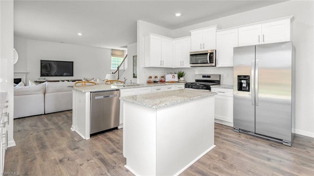 6617 Grogan Hill Rd, Whitsett, NC 27249 - kitchen with appliances with stainless steel finishes, a sink, open floor plan, light stone counters, and white cabinets
