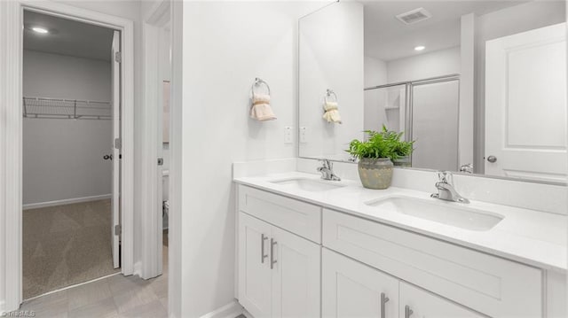 6617 Grogan Hill Rd, Whitsett, NC 27249 - full bath with double vanity, a walk in closet, a shower stall, baseboards, and recessed lighting