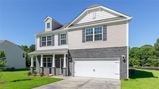 6617 Grogan Hill Rd, Whitsett, NC 27249 - view of front of house with a front yard, concrete driveway, brick siding, an attached garage, and covered porch