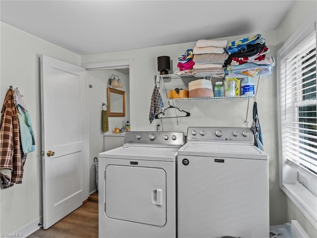 clothes washing area featuring washer and clothes dryer and light wood-type flooring