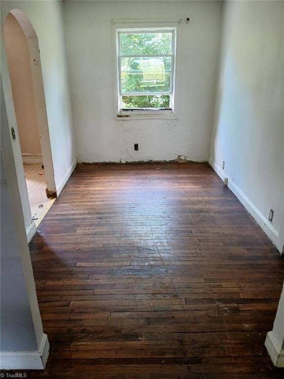 spare room featuring dark wood-style floors and arched walkways