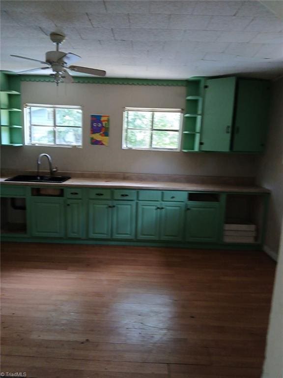 kitchen featuring green cabinets, open shelves, a sink, and a healthy amount of sunlight