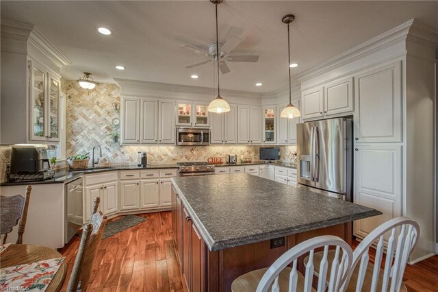 kitchen featuring white cabinetry, a center island, appliances with stainless steel finishes, pendant lighting, and hardwood / wood-style floors