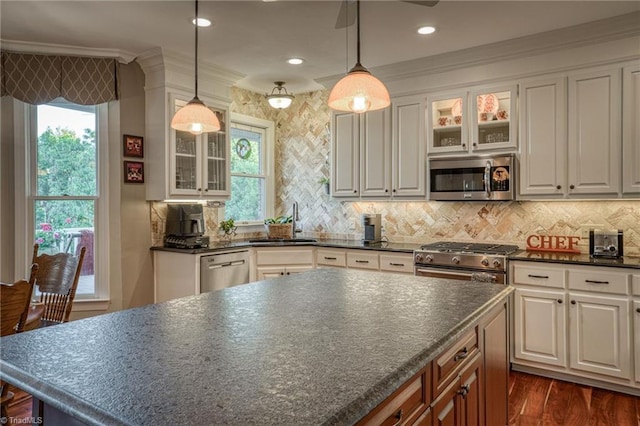 kitchen featuring stainless steel appliances, sink, pendant lighting, and white cabinets