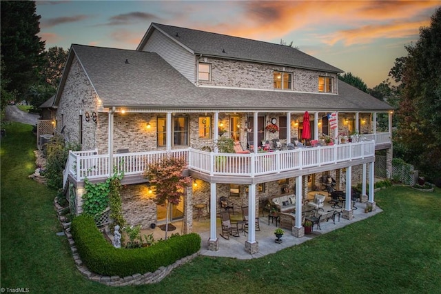 back house at dusk featuring a yard and a patio area