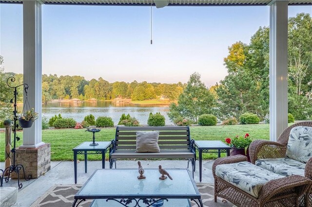 patio terrace at dusk with a water view and a lawn