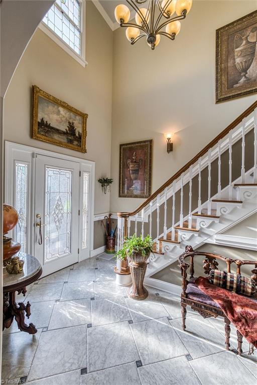 entryway with an inviting chandelier, crown molding, and a high ceiling