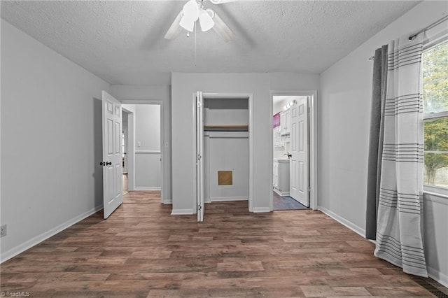 unfurnished bedroom featuring ceiling fan, dark wood-type flooring, and a textured ceiling