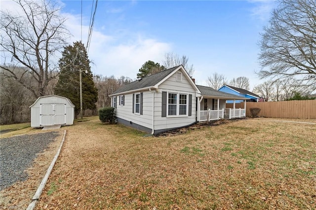 view of front of house featuring a front lawn, covered porch, and a storage shed