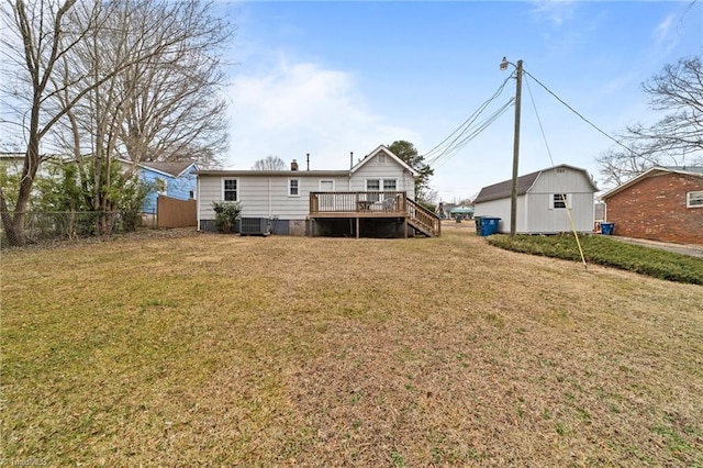 rear view of property with central AC unit, an outbuilding, a lawn, and a deck