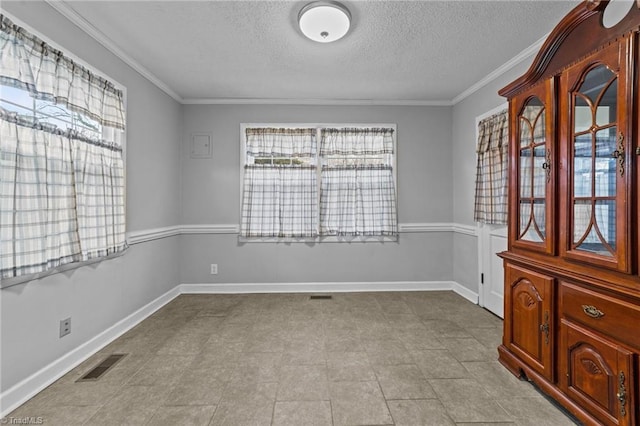 unfurnished room with plenty of natural light, ornamental molding, and a textured ceiling