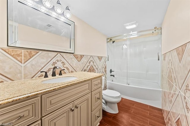 649 W Main St, Franklinville, NC 27248 - full bath featuring toilet, vanity, combined bath / shower with glass door, wood finished floors, and wainscoting
