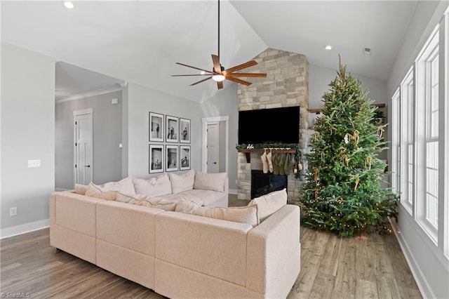 living room with lofted ceiling, a stone fireplace, hardwood / wood-style flooring, ceiling fan, and ornamental molding