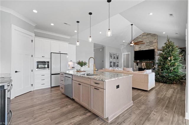 kitchen with white cabinetry, ceiling fan, light stone countertops, an island with sink, and appliances with stainless steel finishes