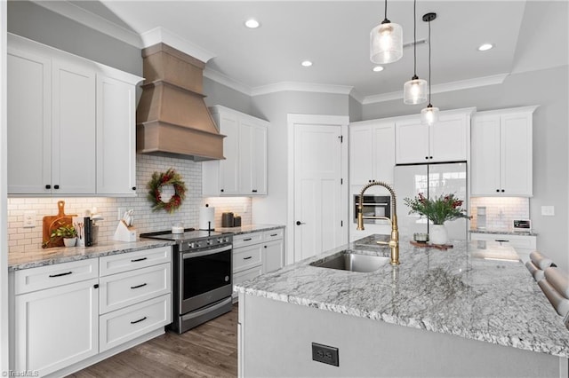 kitchen with appliances with stainless steel finishes, sink, a center island with sink, decorative light fixtures, and white cabinetry