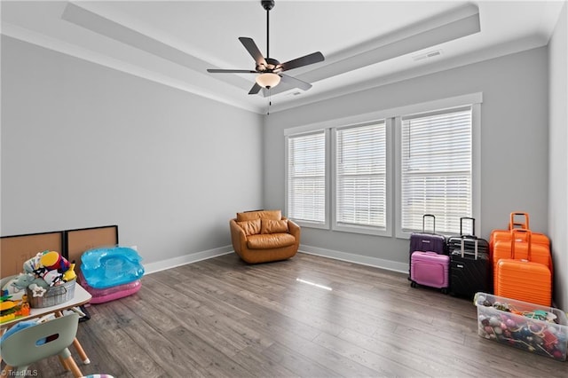 rec room featuring a tray ceiling, ceiling fan, wood-type flooring, and ornamental molding