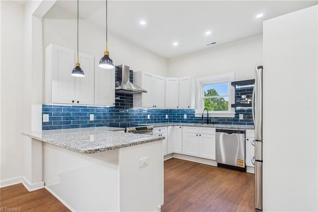1924 E 25th St, Winston-Salem, NC 27105 - kitchen with appliances with stainless steel finishes, wall chimney exhaust hood, a peninsula, dark wood-style flooring, and white cabinetry