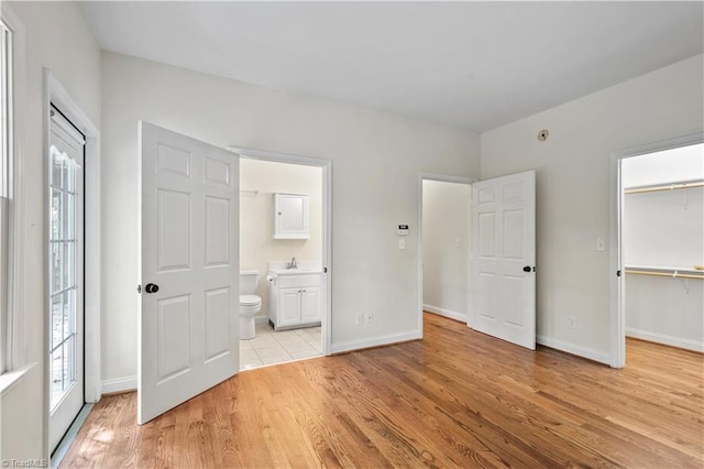 833 E Country Club Rd, Mount Airy, NC 27030 - unfurnished bedroom with light wood finished floors, a spacious closet, baseboards, a sink, and ensuite bath