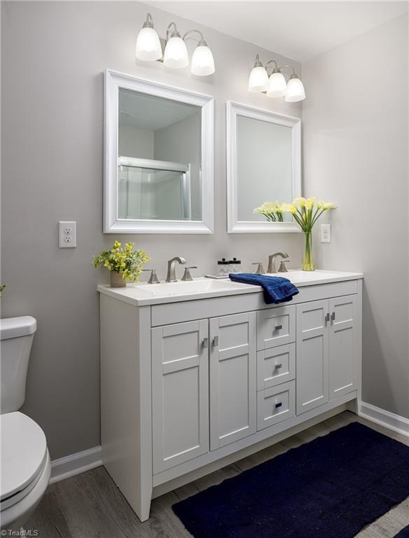 5425 Davis Rd, Walkertown, NC 27105 - full bathroom featuring double vanity, wood finished floors, and an enclosed shower