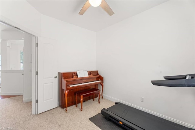 workout area featuring baseboards, light carpet, and a ceiling fan