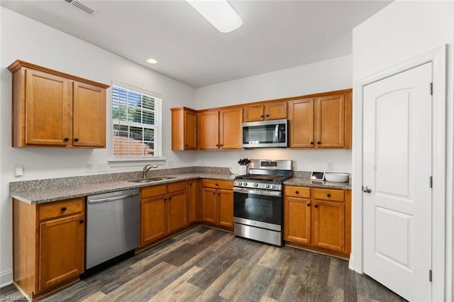 kitchen featuring visible vents, brown cabinets, a sink, dark wood finished floors, and stainless steel appliances