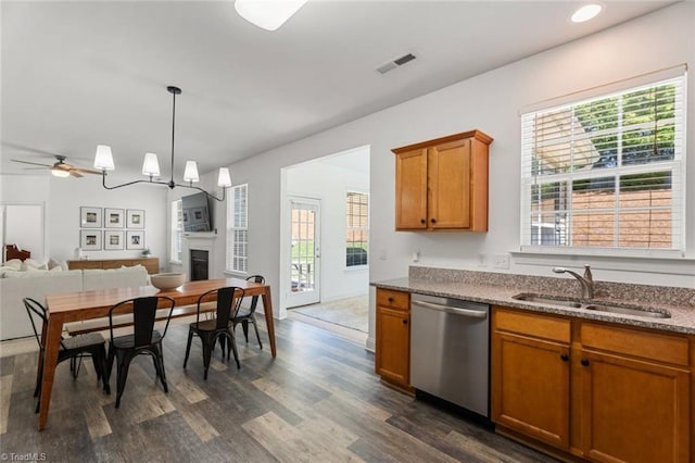 kitchen featuring dark wood-style flooring, a sink, brown cabinetry, stainless steel dishwasher, and visible vents