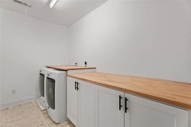 washroom with cabinet space, separate washer and dryer, baseboards, and visible vents