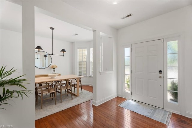 entrance foyer with baseboards, wood-type flooring, a chandelier, and visible vents