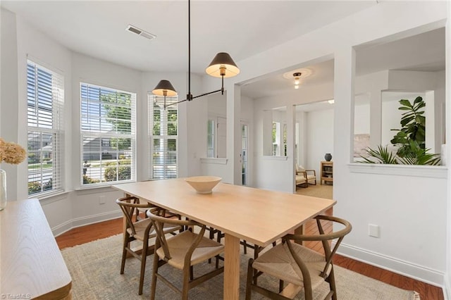 dining space with baseboards, visible vents, and wood finished floors