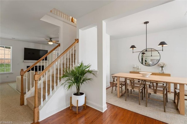 stairway featuring a ceiling fan, baseboards, and wood finished floors