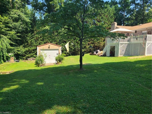 view of yard featuring a garage, an outbuilding, and a deck