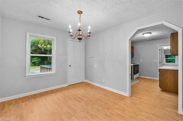 1655 Oakleigh Rd, Mcleansville, NC 27301 - unfurnished room featuring a textured ceiling, light wood-type flooring, a chandelier, and arched walkways