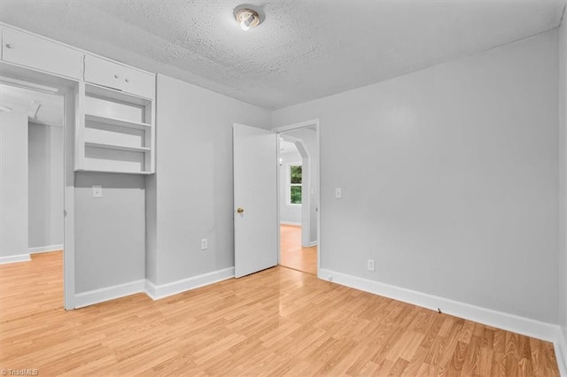 1655 Oakleigh Rd, Mcleansville, NC 27301 - unfurnished bedroom with light wood-style floors, a textured ceiling, and arched walkways