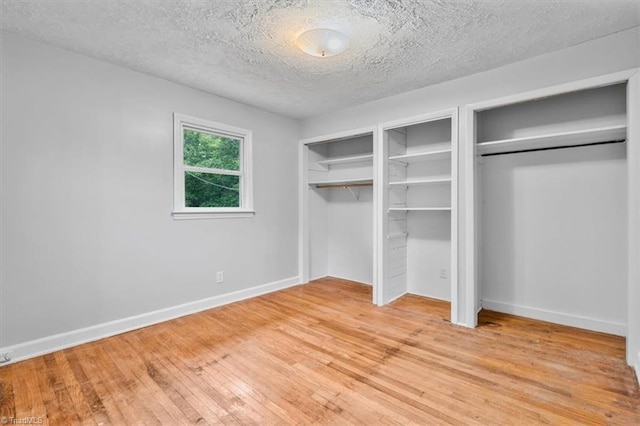 1655 Oakleigh Rd, Mcleansville, NC 27301 - unfurnished bedroom with two closets, light wood finished floors, and a textured ceiling
