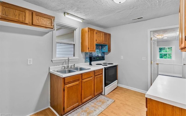 1655 Oakleigh Rd, Mcleansville, NC 27301 - kitchen with electric stove, light countertops, light wood-type flooring, brown cabinetry, and a textured ceiling