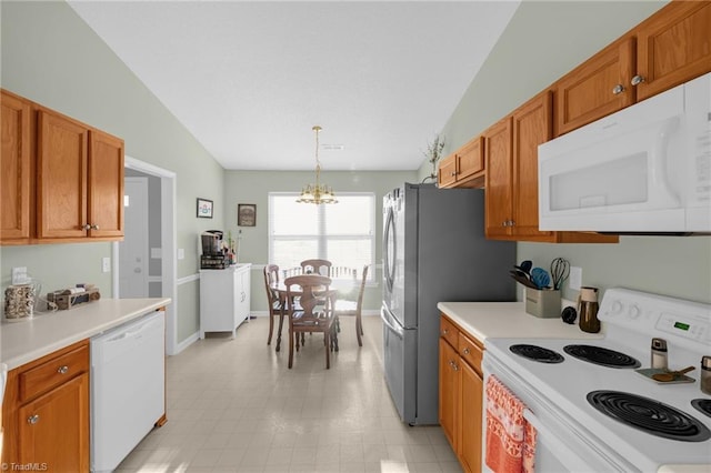 kitchen featuring white appliances, an inviting chandelier, hanging light fixtures, and vaulted ceiling