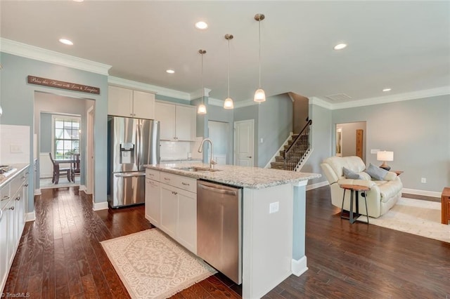 113 Crestbourne Ct, Stokesdale, NC 27357 - kitchen with stainless steel appliances, a kitchen island with sink, white cabinets, light stone counters, and ornamental molding
