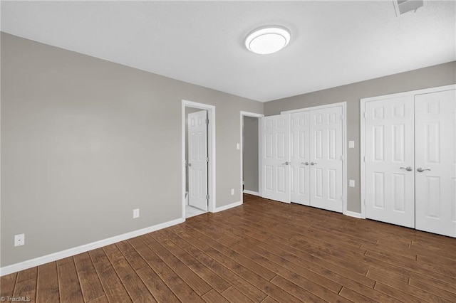 5660 W Market St Unit A, Greensboro, NC 27409 - unfurnished bedroom featuring two closets, wood finished floors, and baseboards