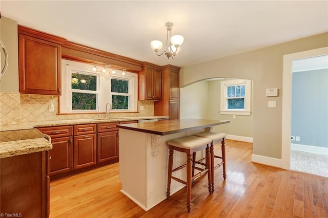 kitchen with backsplash, sink, a kitchen island, and light wood-type flooring