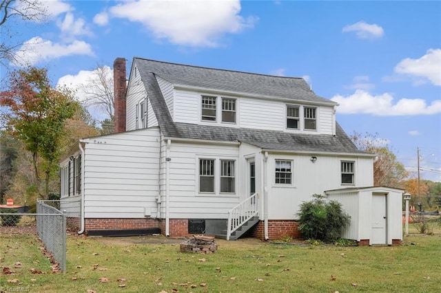 rear view of property with a lawn and a storage shed