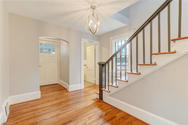 entryway with baseboard heating, a chandelier, and light wood-type flooring