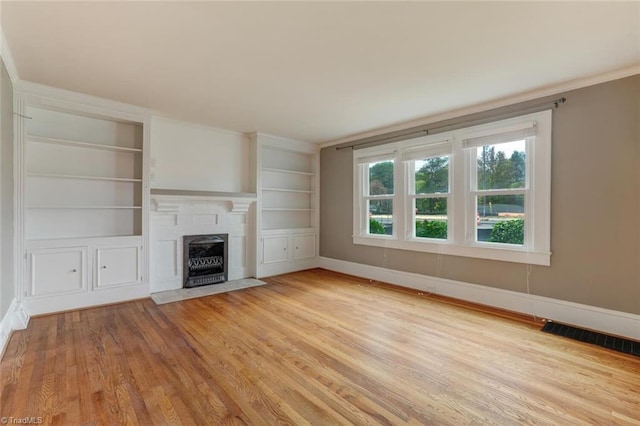 unfurnished living room with light hardwood / wood-style floors, built in features, and ornamental molding