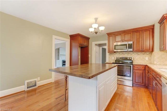 kitchen featuring a center island, an inviting chandelier, a kitchen breakfast bar, light hardwood / wood-style flooring, and appliances with stainless steel finishes